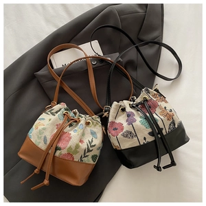 Detail view of two floral jacquard bucket bags with drawstring and leather base
