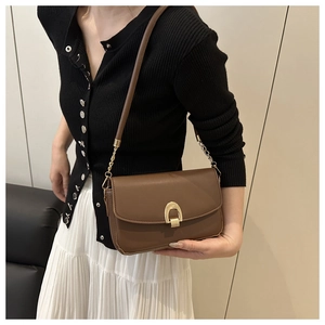Détail du sac à main vintage en cuir marron avec fermoir fer à cheval doré et chaîne