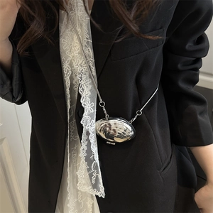 Silver metallic shell bag with hammered texture and snake chain shown on a model