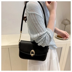Détail d'un sac bandoulière minimaliste en similicuir noir avec boucle dorée