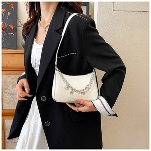 Detail of white quilted underarm bag with silver butterfly chain shown on model