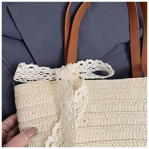 Detail of hand-woven straw texture and exquisite white lace bow on a large tote bag