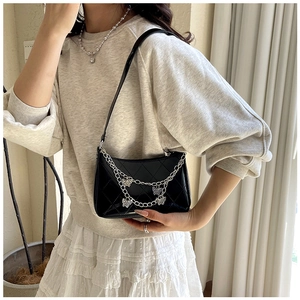 Detail of black quilted shoulder bag with silver butterfly chain charms and glossy finish
