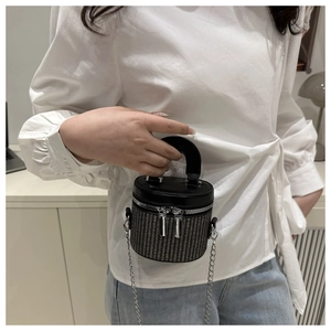 Detail of woven bucket bag featuring dual zippers and elegant silver chain strap