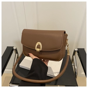 Détail du sac bandoulière en cuir caramel avec boucle fer à cheval dorée et chaîne