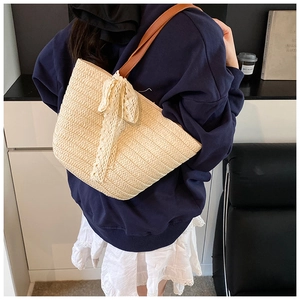 Straw tote bag with lace bow and leather straps shown from a stylish back view