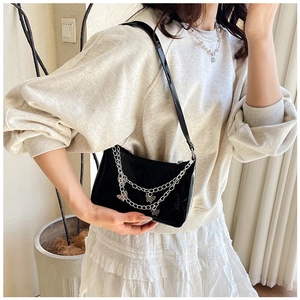 Close-up of black quilted shoulder bag with glossy finish and silver butterfly chains