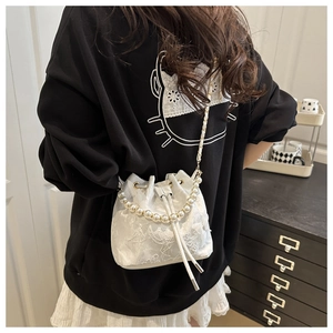 Detailed shot of white lace bucket bag featuring pearl handle and drawstring closure