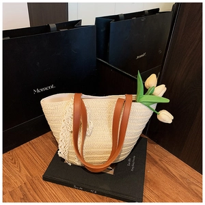 Detail of straw woven tote bag featuring white lace trim and brown leather handles