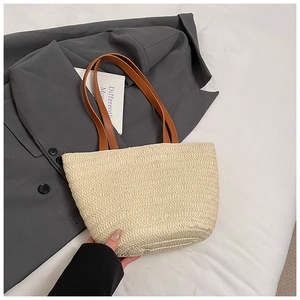 Detailed close-up of woven beige straw handbag texture with brown leather shoulder straps