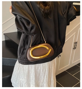 Brown leather crossbody bag with gold C-buckle and chain strap on a model