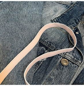 Detail of pink leather shoulder strap with neat stitching on denim background