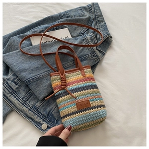 Detail of colorful striped woven mini bag with brown leather handles and FASHION patch