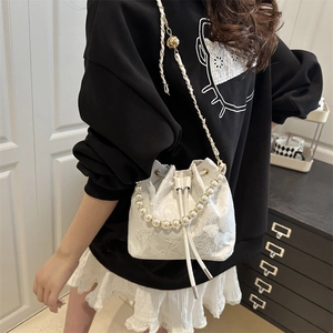 White bucket bag with butterfly lace and pearl chain shown on model in a chic room