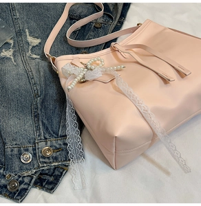 Detailed shot of pink faux leather tote bag with pearl bow and lace ribbon accessory