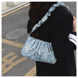 Detail of light blue sequined underarm bag with pleated strap and silver stripes texture