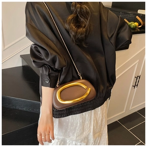 Dark brown leather box bag with bold gold metal ring and slim chain strap on model