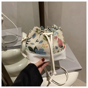 Detail of floral jacquard drawstring bucket bag with white leather trim and gold metal eyelets