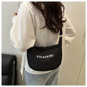 Detail of black canvas crescent tote bag with letter print worn by model from behind