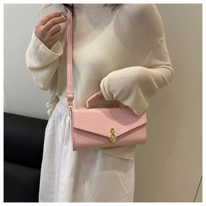 Detailed view of pink woven leather bag featuring a gold infinity buckle and shoulder strap