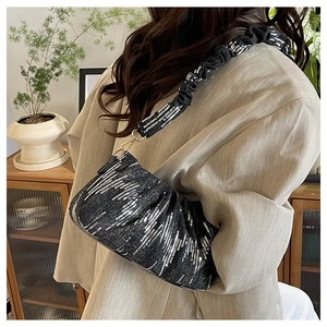 Detail of black sequined scrunchie shoulder bag featuring cloud pleated design and silver stripes