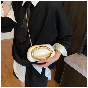 Close-up of a white pebble leather handbag with a gold circular handle worn by a model