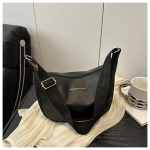 Detail of black PU crescent bag showing golden hardware and textile shoulder strap