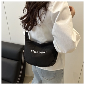 Close-up of black canvas hobo bag with white lettering on model for size and fit detail