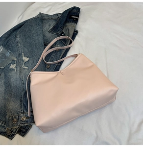 Close-up of a nude pink faux leather tote bag with an adjustable strap and bow charm