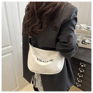 Detail view of white crescent bag with YICAIAINI lettering on a black blazer