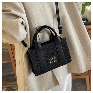 Detail of black glitter crossbody bag with THE BAG logo and adjustable gold buckle strap