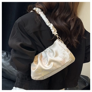 Detailed view of cream ruched strap and floral pattern on retro style satin shoulder bag