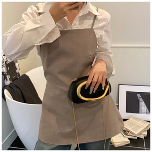 Detail of a black half-moon clutch bag with oversized gold circular metal handle