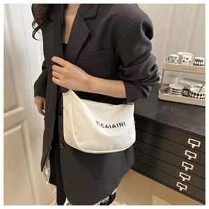 Detail of white canvas crescent bag with black letter print and adjustable shoulder strap