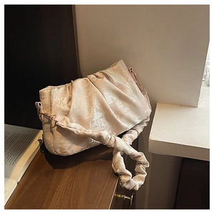 Detail of beige jacquard cloud bag with pleated handle and elegant retro patterns