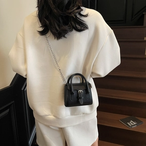 Vintage black mini handbag with silver buckle and metal chain strap worn on crossbody