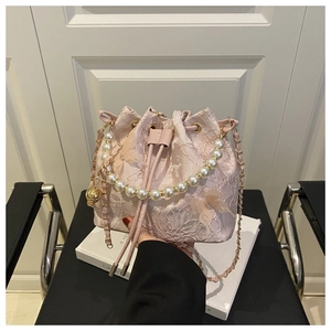 Detail of pink lace bucket bag featuring 3D butterfly accents and premium pearl handle