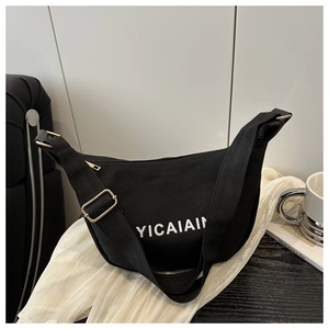Detailed close-up of black canvas crescent bag with golden metal buckle and letter print