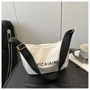 Close-up of a white canvas crescent bag with black strap and golden metal buckle details