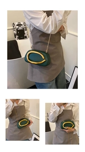 Detail of dark green matte shoulder bag featuring a large gold metallic circular handle