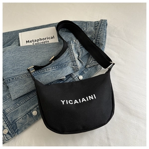 Close-up of black canvas hobo bag with white letter print and adjustable shoulder strap