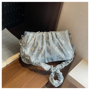 Detail of light blue sequined denim cloud bag with pleated straps on wooden shelf