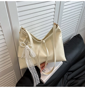 Detail der cremeweißen PU-Leder-Einkaufstasche mit eleganter Spitze und Perlen-Anhänger