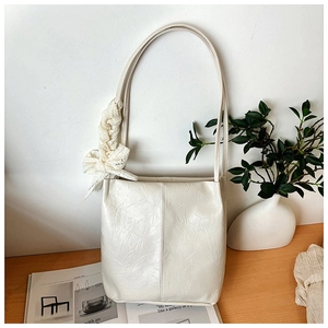 Close-up of cream white bucket bag with elegant lace bow detail and pleated texture