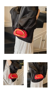 Detail of red semicircular crossbody bag with large gold arc buckle and chain strap