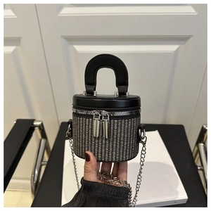 Detailed close-up of a woven cylinder box bag with leather lid and silver chain strap