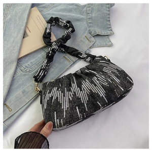 Macro detail of dark grey denim pleated bag with shimmering silver sequins and gold metal hooks