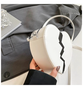 Détail du sac à main blanc en forme de cœur avec motif éclair noir et fermeture éclair en métal