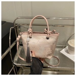 Gros plan détaillé du sac seau en jacquard rose avec broderie et pompon traditionnel