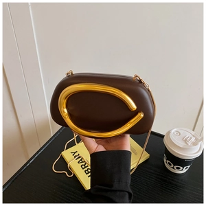Detail of a dark brown leather clutch with gold metal horse-bit handle and chain strap